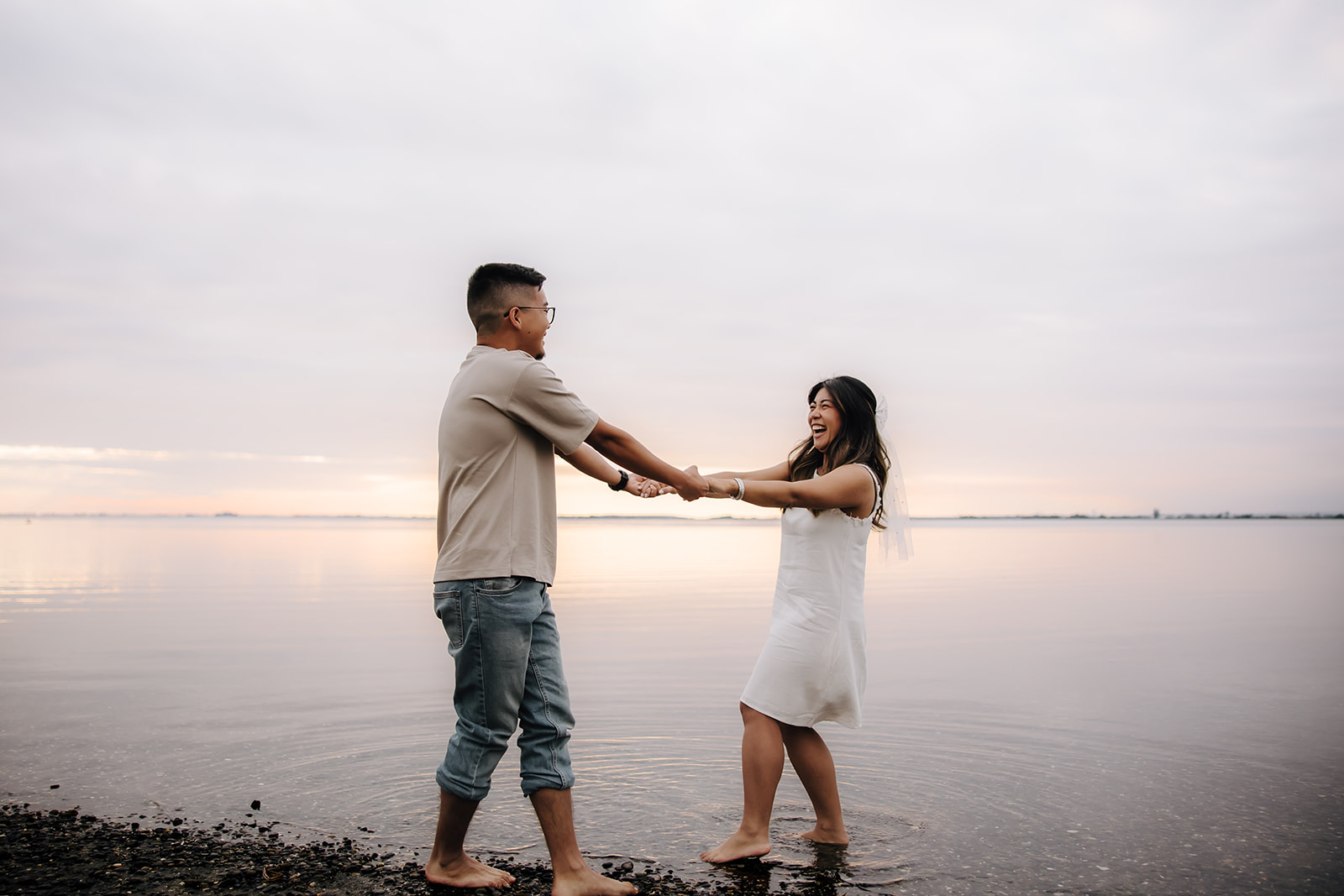 Engaged couple dancing on the beach smiling and laughing