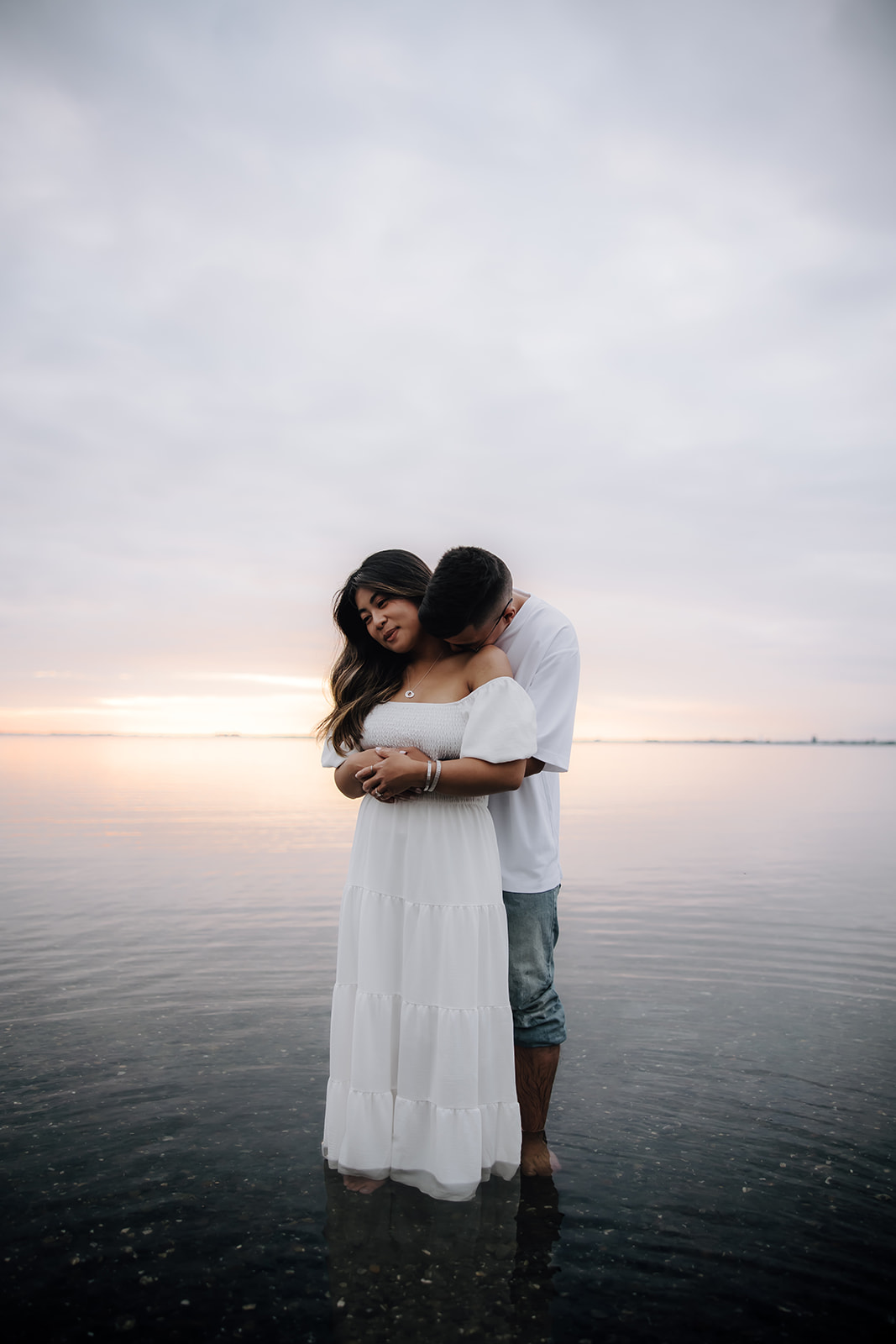 Engaged couple hugging standing in the ocean at Crescent beach