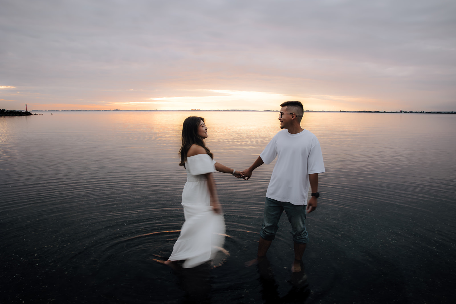 Engaged couple holding hands standing in the ocean at Crescent beach