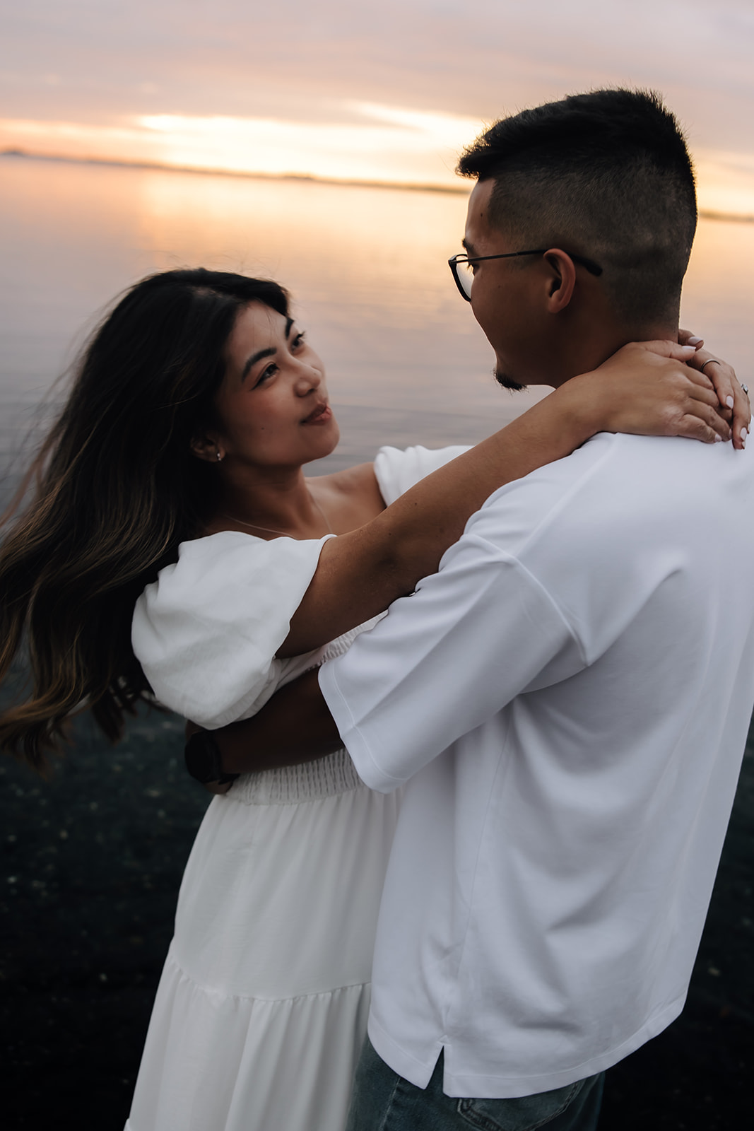 Engaged couple dancing in the ocean during sunset