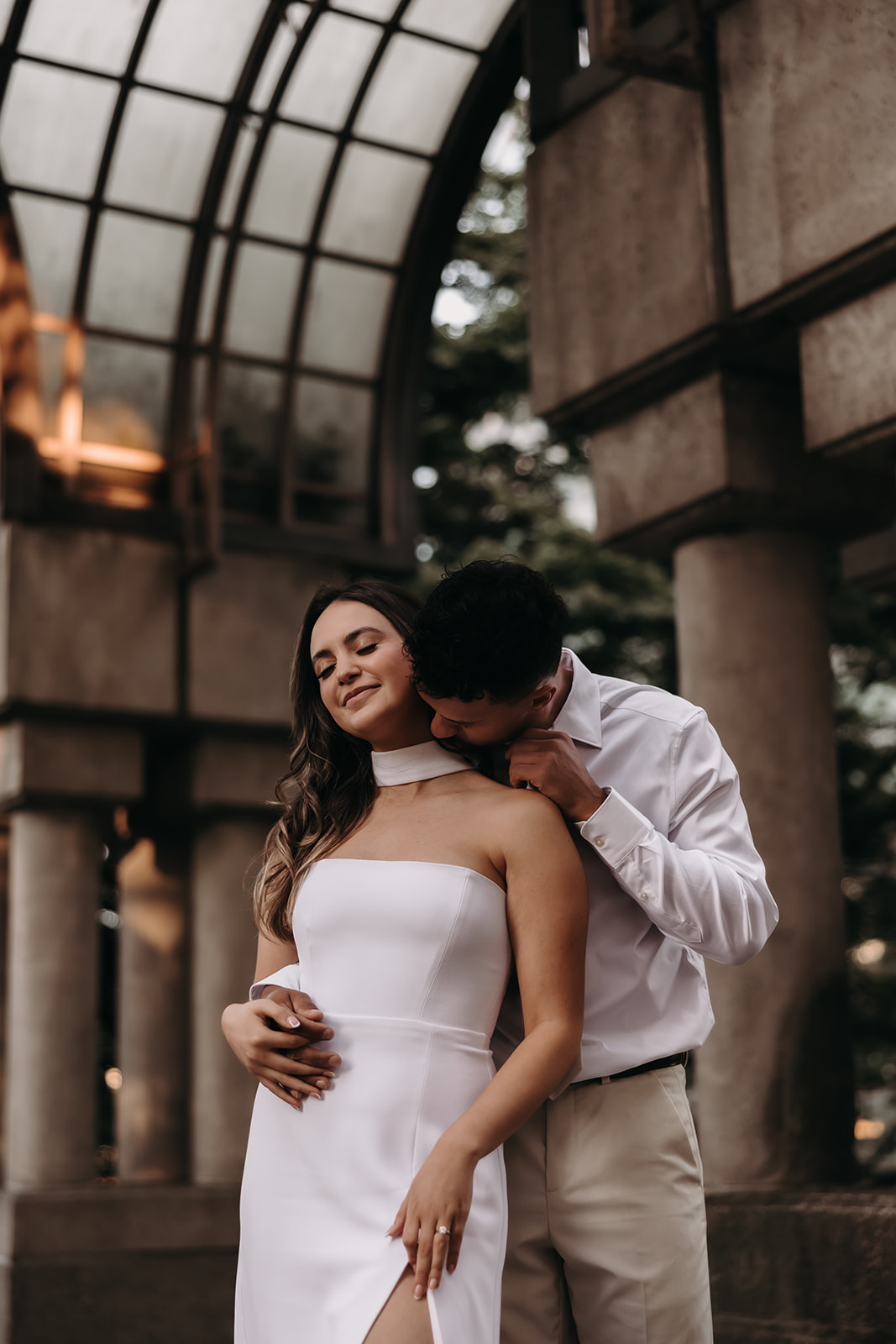 Romantic moment as the groom kisses the bride's neck in an elegant downtown engagement session.