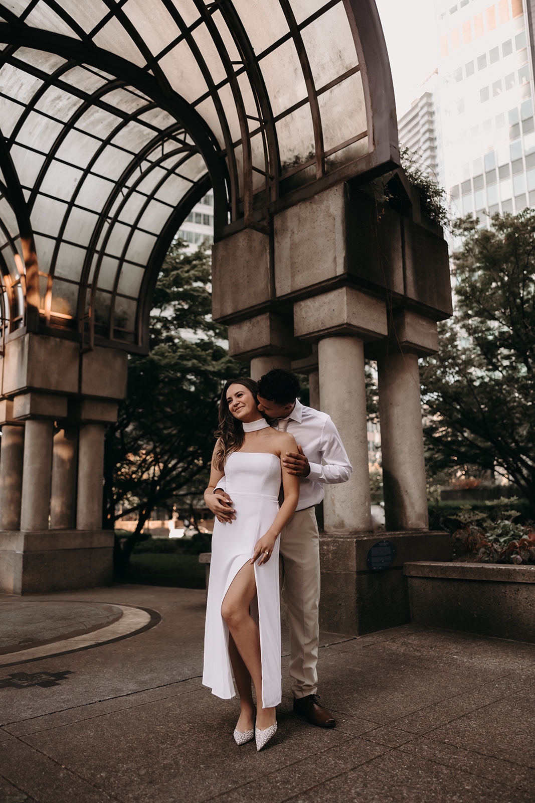 A couple embraces under a modern archway during their downtown engagement photos.