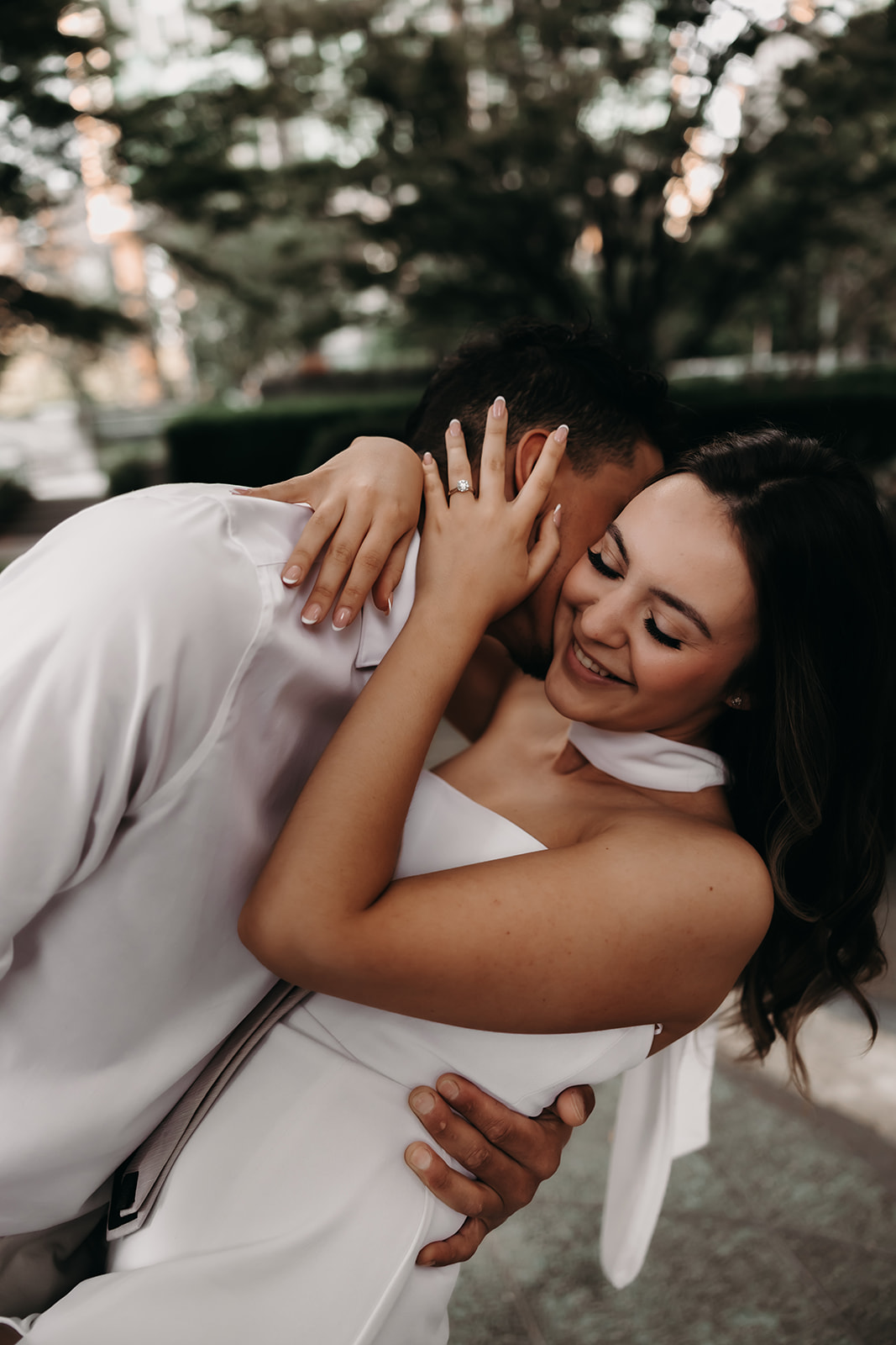 Candid laugh shared by a couple, embracing closely for their downtown engagement photos.