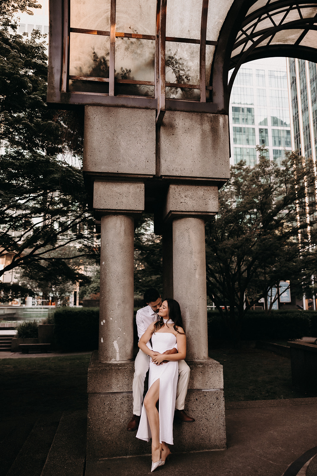 A stylish couple posing in front of modern architecture as they enjoy their downtown engagement photos.