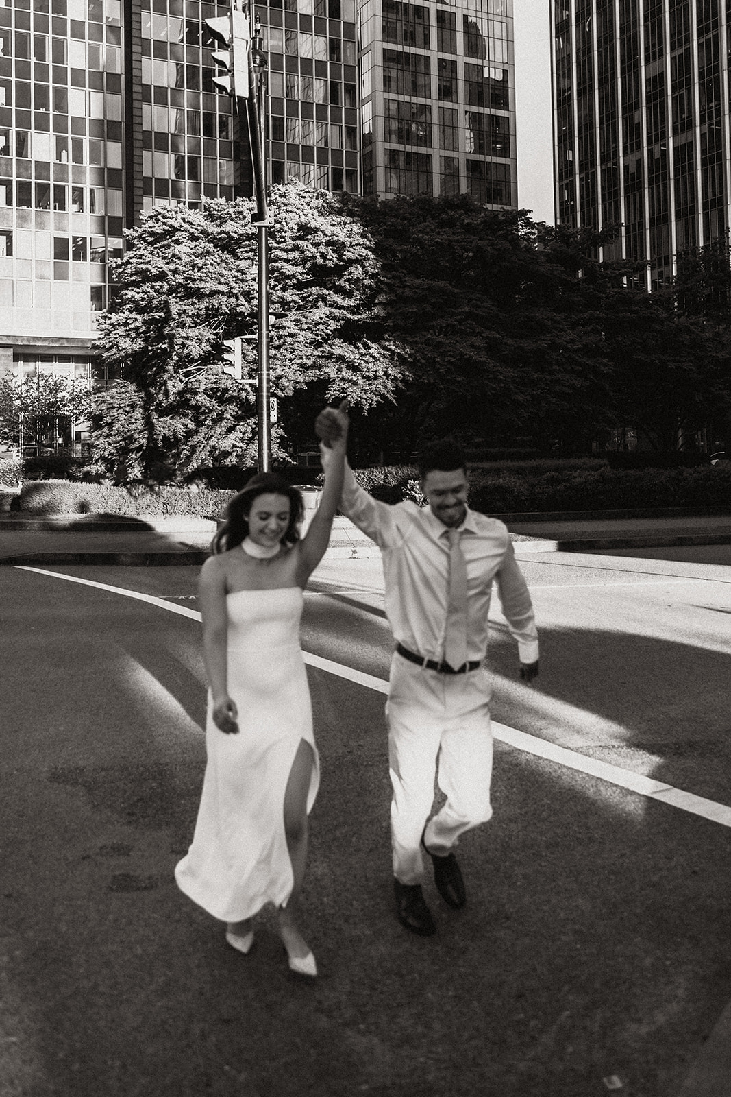 A couple walking hand in hand across a city street, capturing a candid moment during their downtown engagement photos.