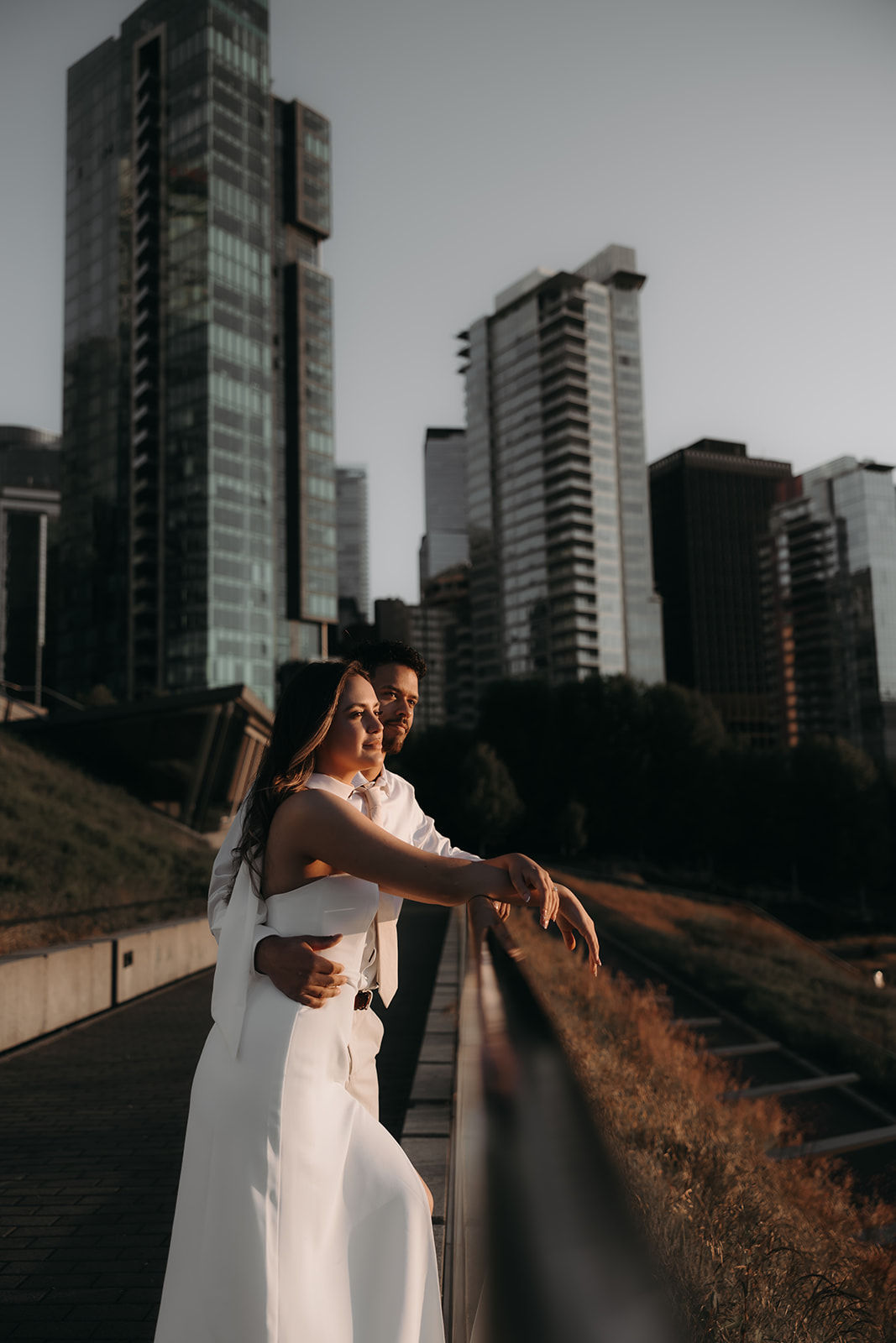 Romantic moment captured at sunset as a couple embraces in front of a city skyline.