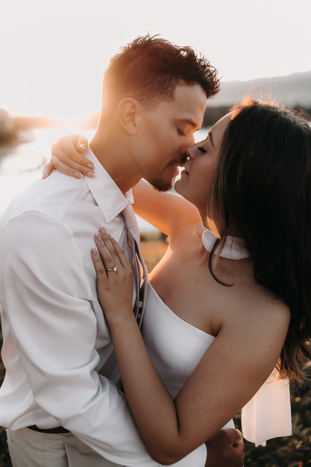 Close-up of a couple sharing a kiss at sunset, their engagement ring sparkling in the light.