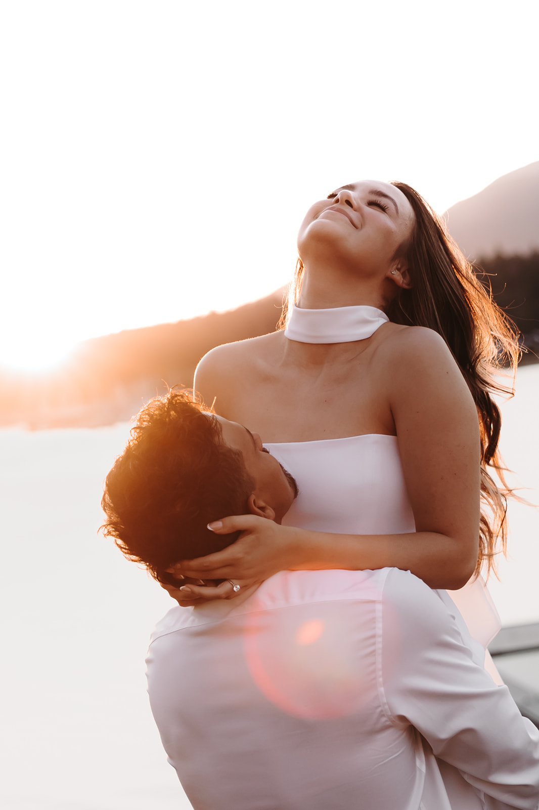 A joyful moment of a woman smiling as she is lifted in the air, highlighting the love and energy of their downtown engagement photos.