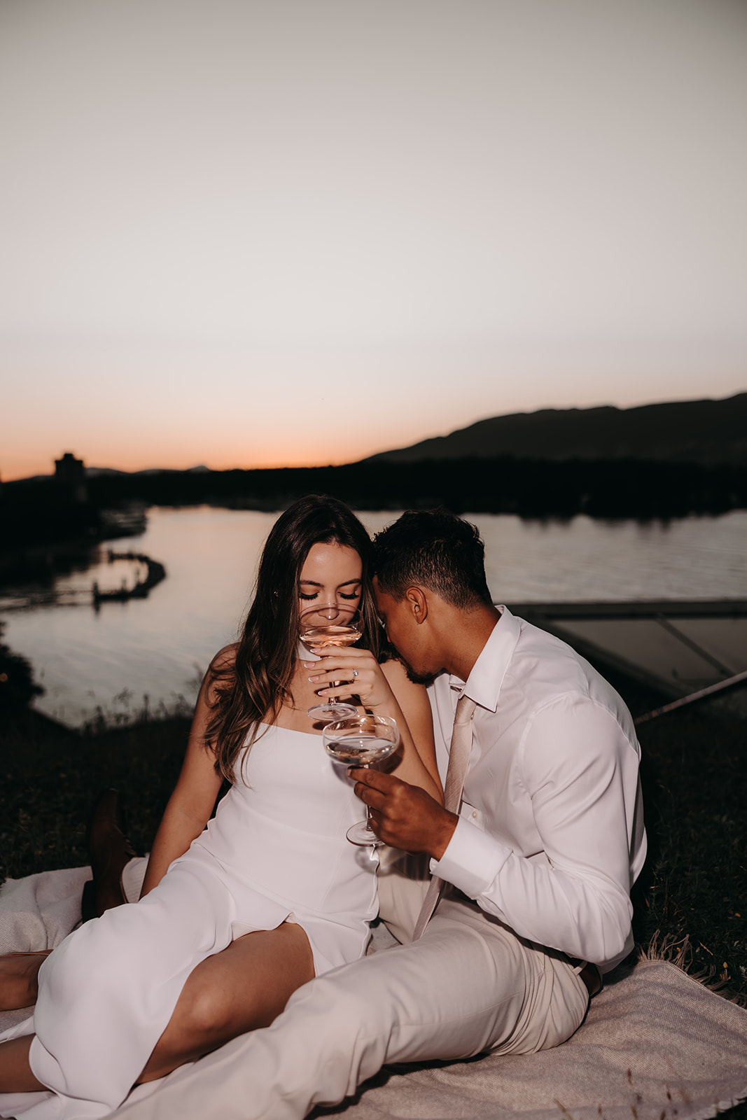 A romantic evening as the couple enjoys a glass of champagne on a blanket by the water during their downtown engagement photos session.