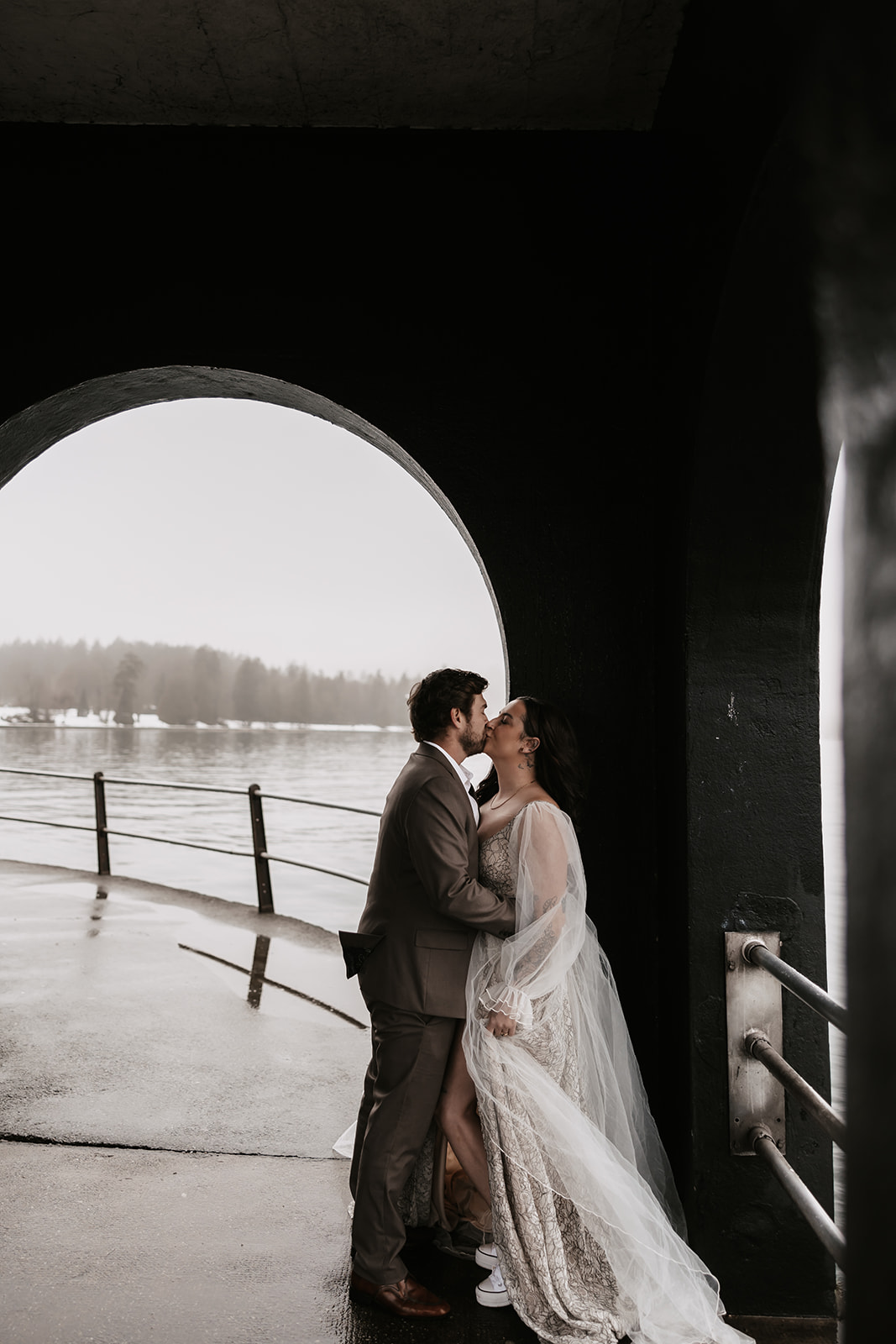 The bride and groom share an intimate kiss under the archway during their rainy Vancouver elopement.