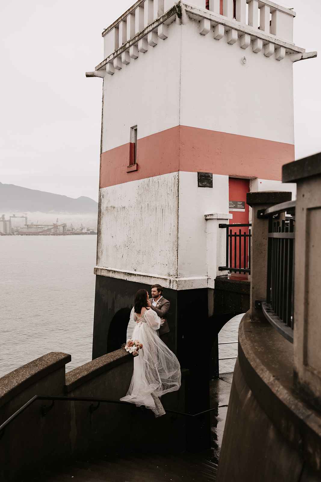 A picturesque shot of the couple standing near a lighthouse during their Vancouver elopement.