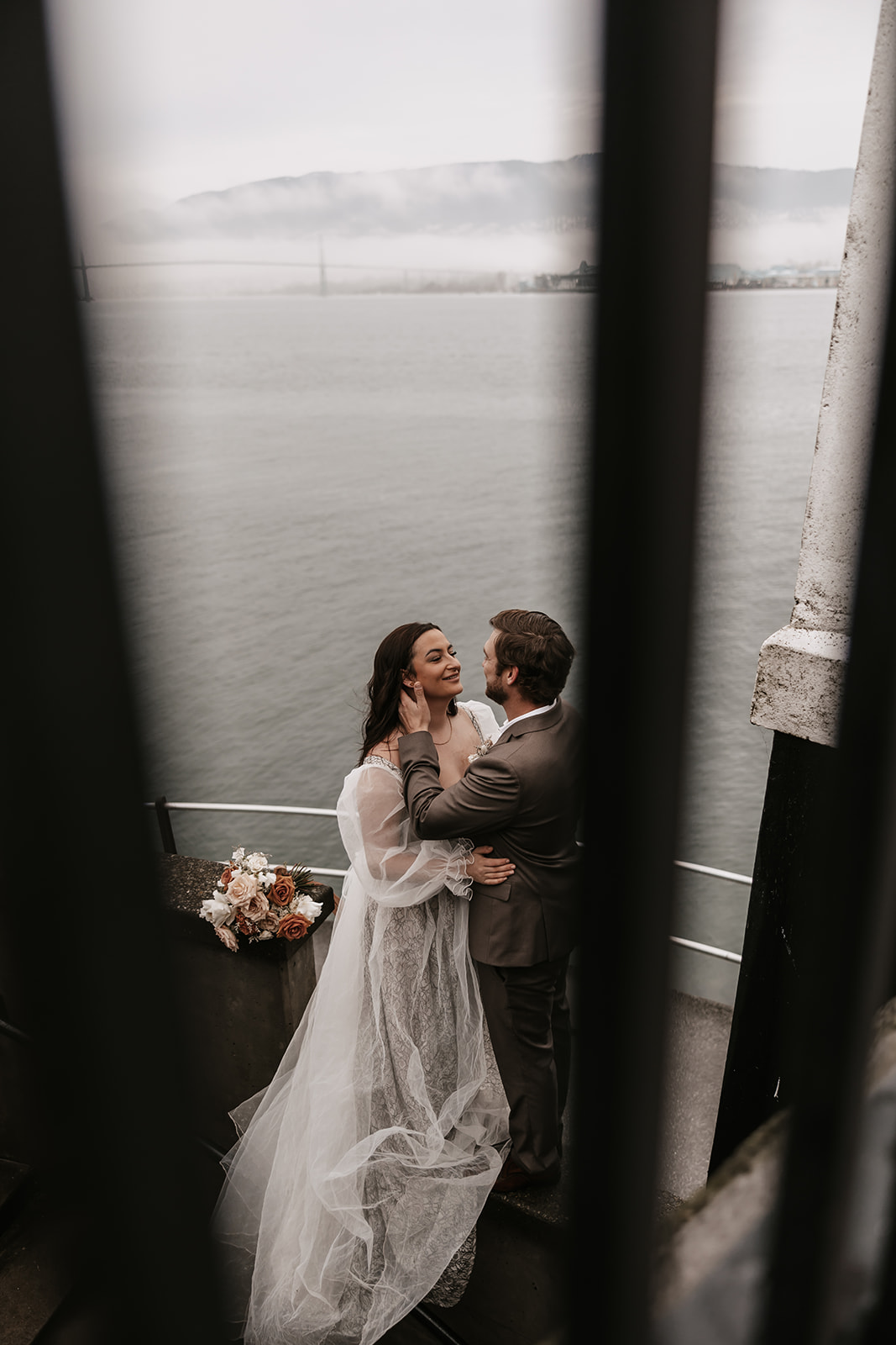 A candid moment as the bride and groom share a quiet kiss through the bars of the lighthouse stairs.