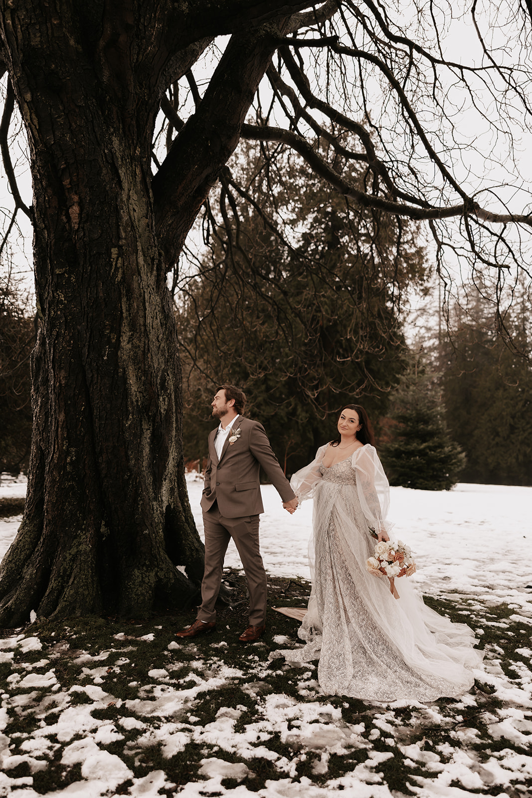 The bride and groom holding hands, looking into each other’s eyes, surrounded by snow-covered ground during their winter elopement in Vancouver.