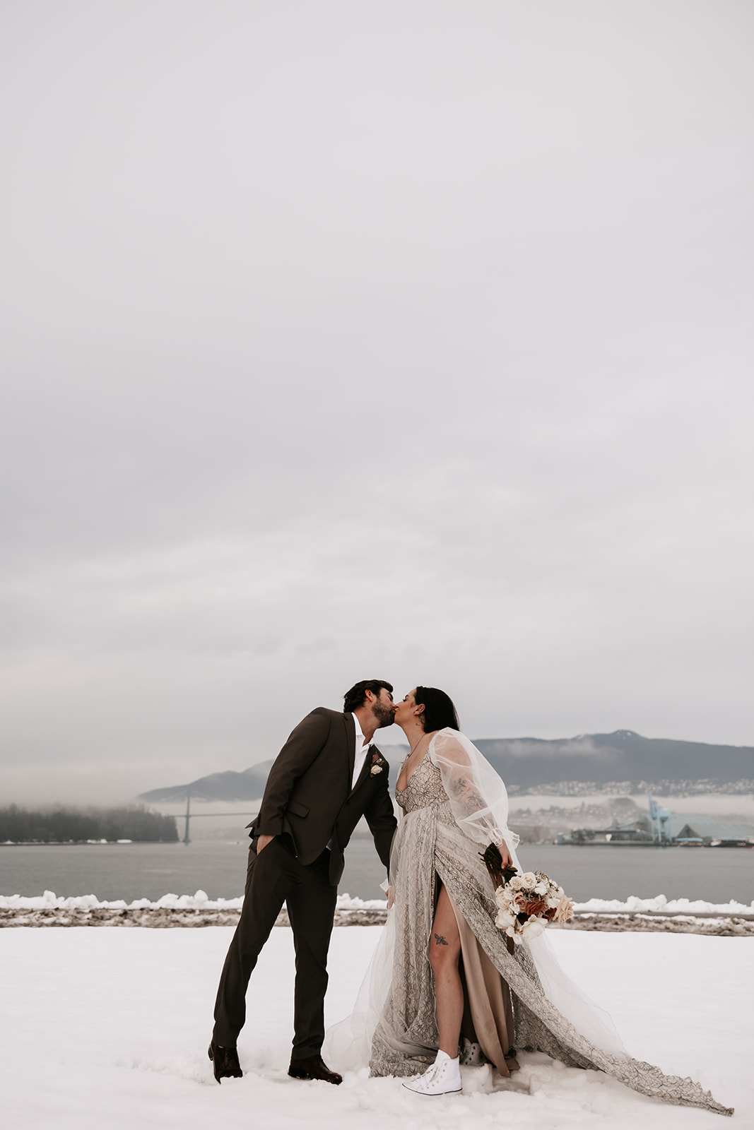 The bride and groom kissing surrounded by snow-covered ground during their winter elopement in Vancouver.