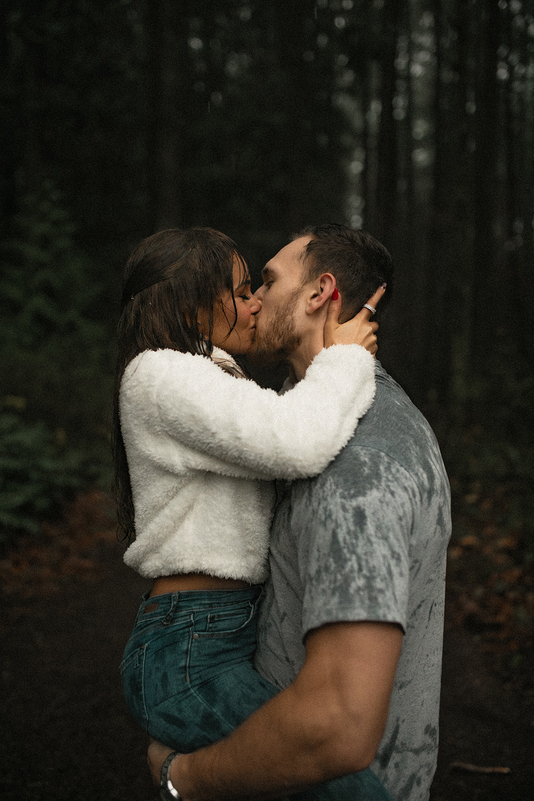 A close-up shot of a couple sharing a tender kiss in the rain, capturing the essence of romantic rainy day couple pictures. Their expressions are filled with joy and love, perfectly embodying the fun couple photoshoot vibe.