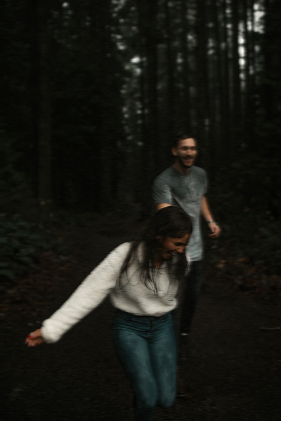 A playful moment as the couple runs hand in hand through the forest, the rain creating a magical atmosphere. This image exemplifies fun couple photoshoot ideas that embrace spontaneity and joy.