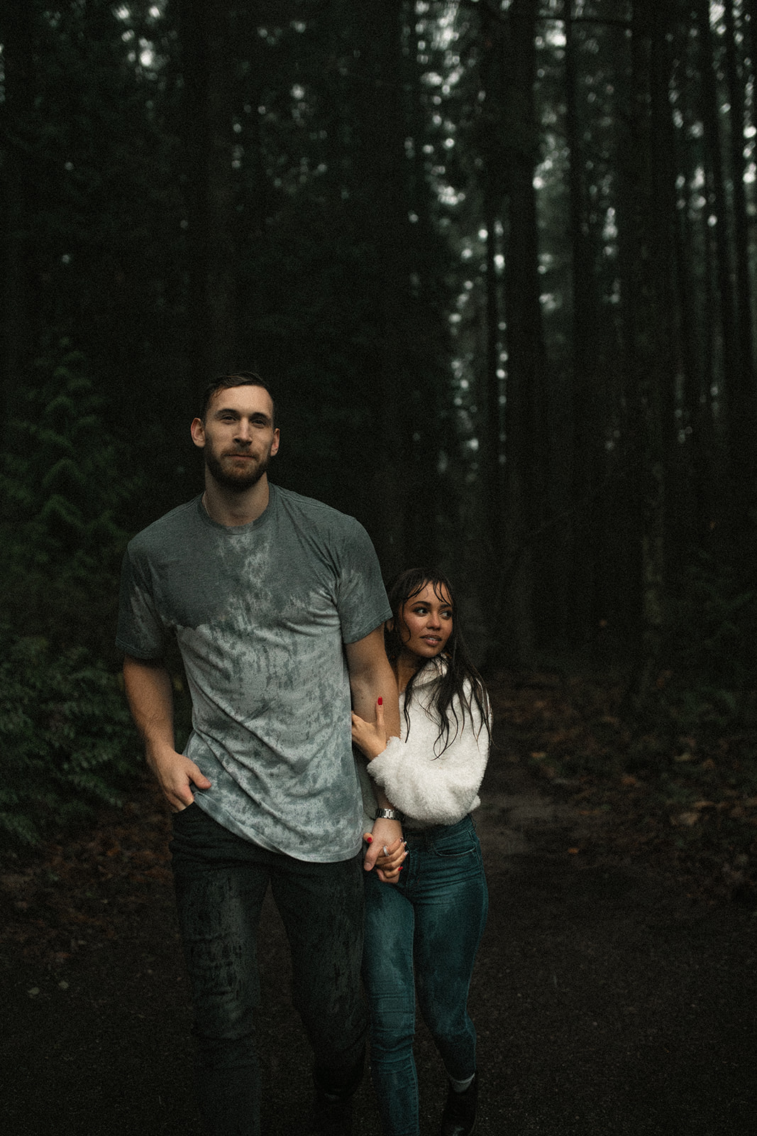 The couple walking through a misty forest, hand in hand, as the rain creates a dreamy atmosphere. This rainy day couple picture highlights their connection and the adventurous side of fun couple photoshoot ideas.