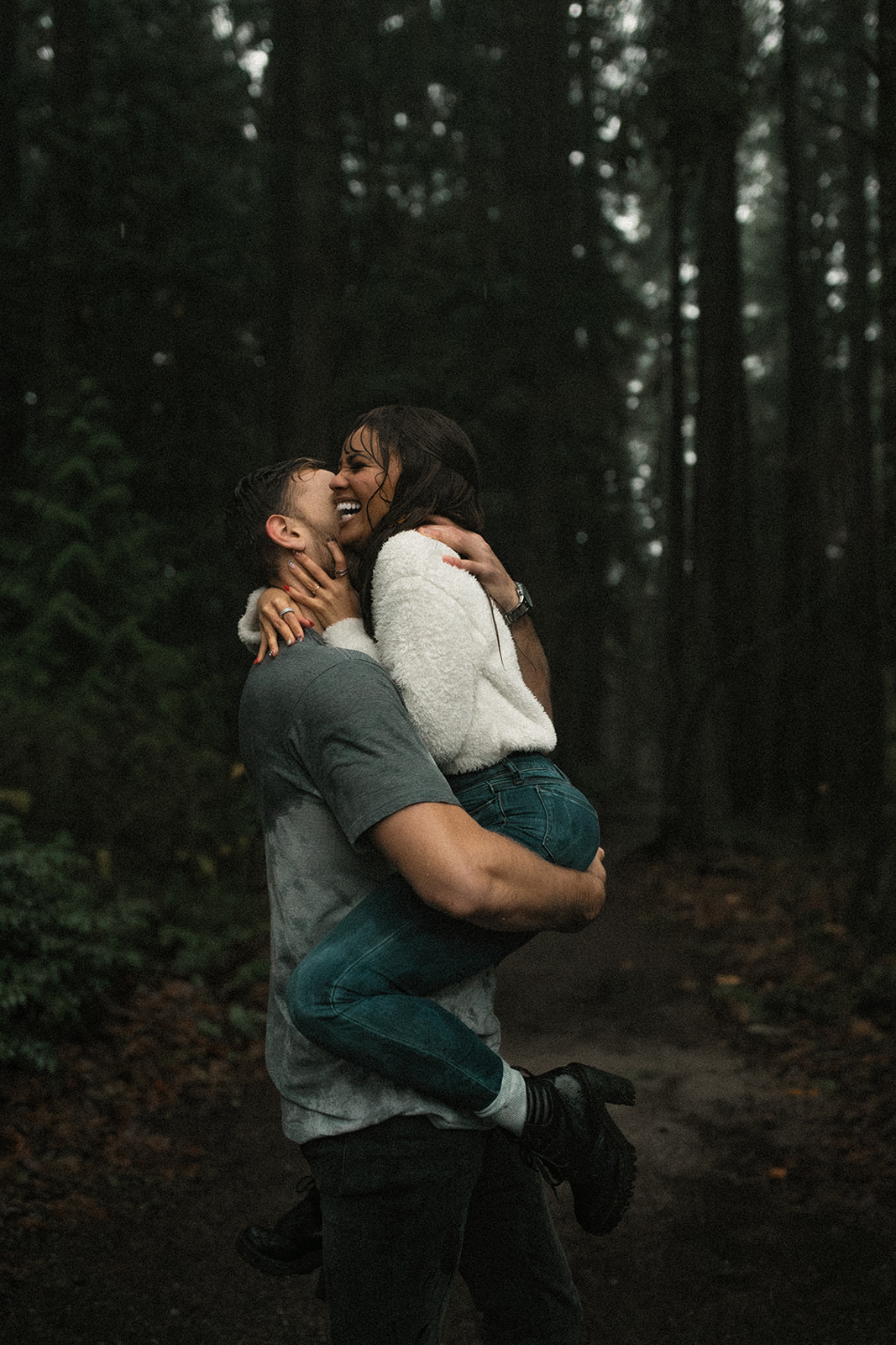 The couple shares a sweet, tender moment as they embrace, with the woman wrapping her arms around the man's neck. The dark, wet environment adds an element of romance to this rainy day couple picture. Their joyful expressions highlight the fun couple photoshoot ideas that celebrate love in every weather condition, emphasizing that a little rain can lead to unforgettable memories.