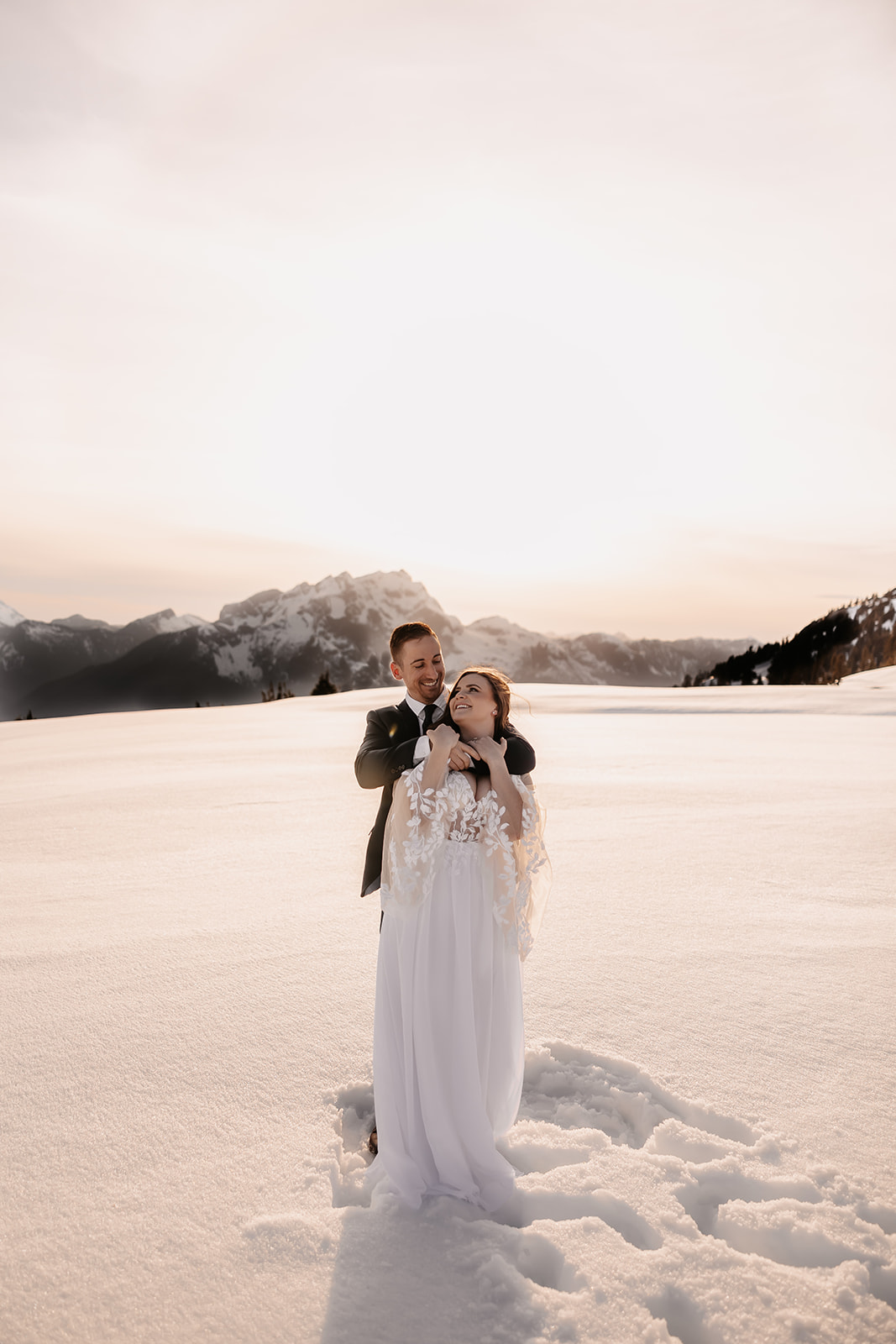 Couple embracing in the snow during their helicopter elopement in the mountains of BC, with stunning peaks in the background.