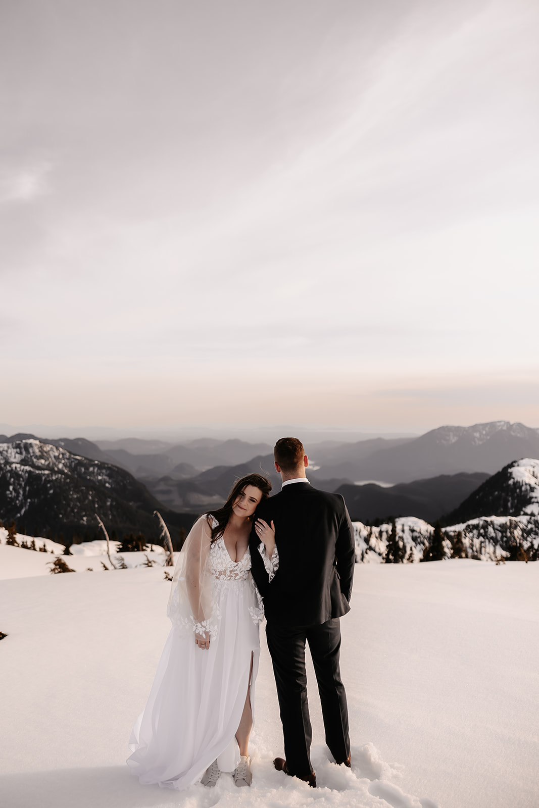 Close-up of the couple sharing a tender moment near their helicopter, with snow-capped mountains creating a stunning backdrop.