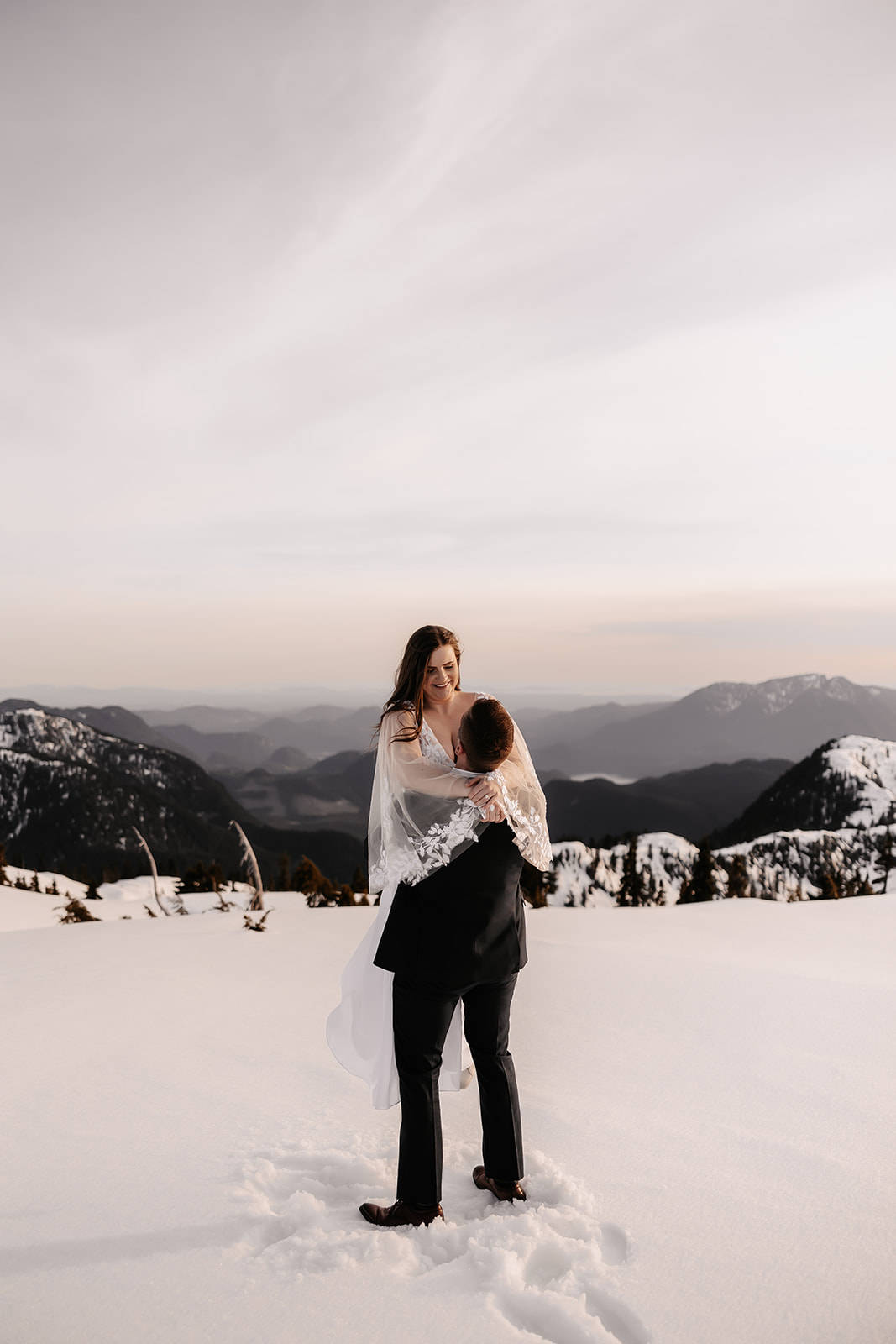 Joyful couple dancing with the breathtaking mountain scenery surrounding them.