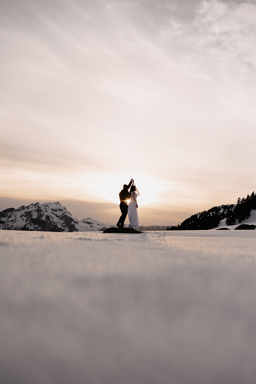 The couple dancing together on a snow-covered mountain, encapsulating the intimate moments of their helicopter elopement.