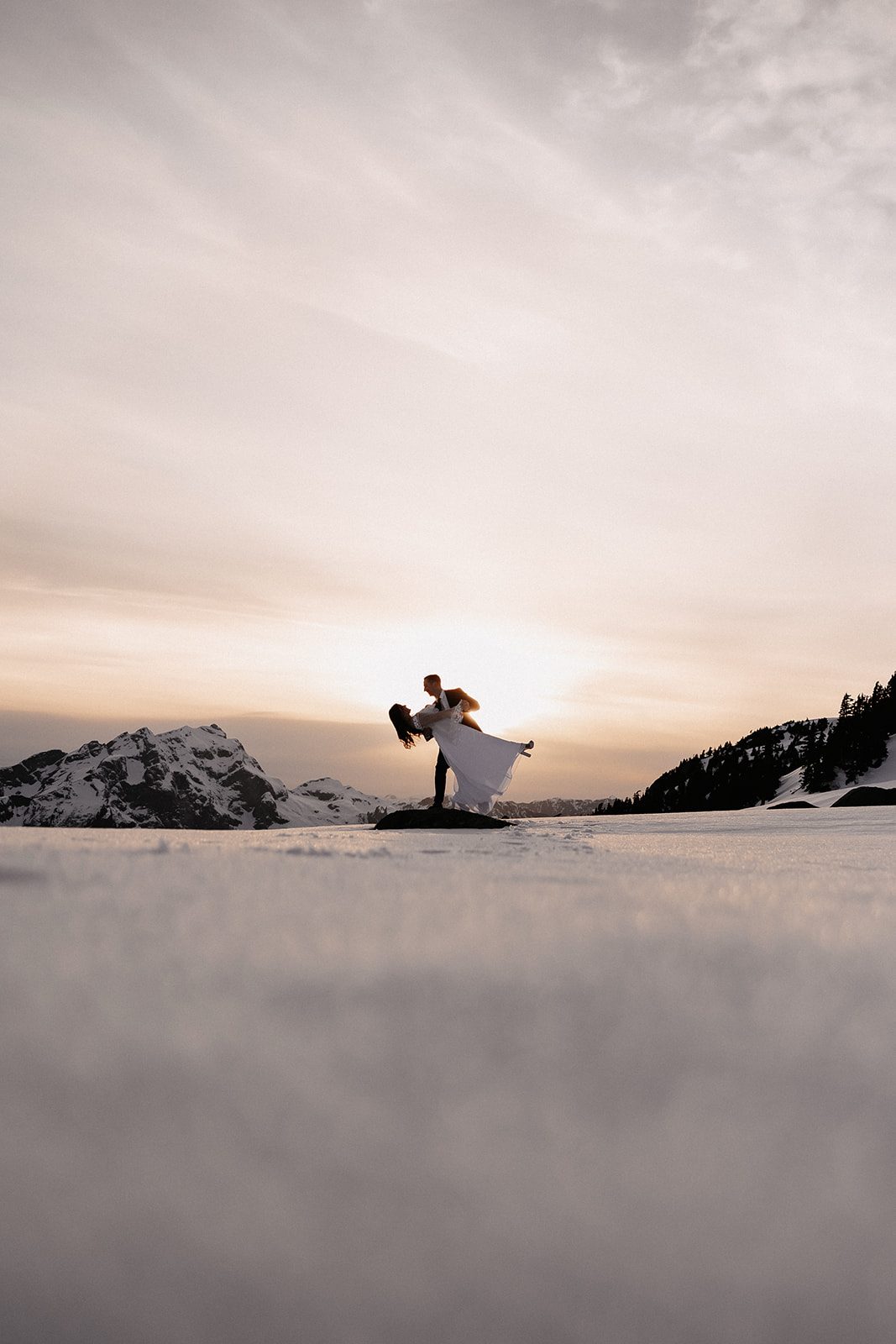 The couple dancing together on a snow-covered mountain, encapsulating the intimate moments of their helicopter elopement.