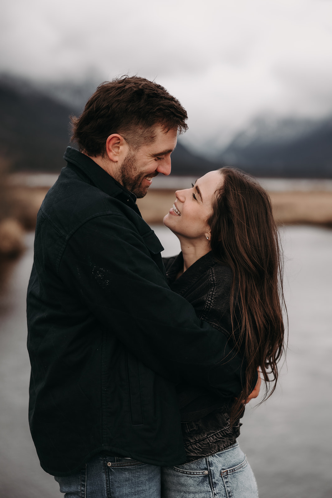 This close-up image showcases the couple sharing a tender moment as they embrace, their foreheads touching. Their expressions are filled with joy and affection, emphasizing the deep connection they share. The muted tones of the background complement their cozy look, perfectly encapsulating the warmth and emotion often found in heartfelt fall engagement photos.