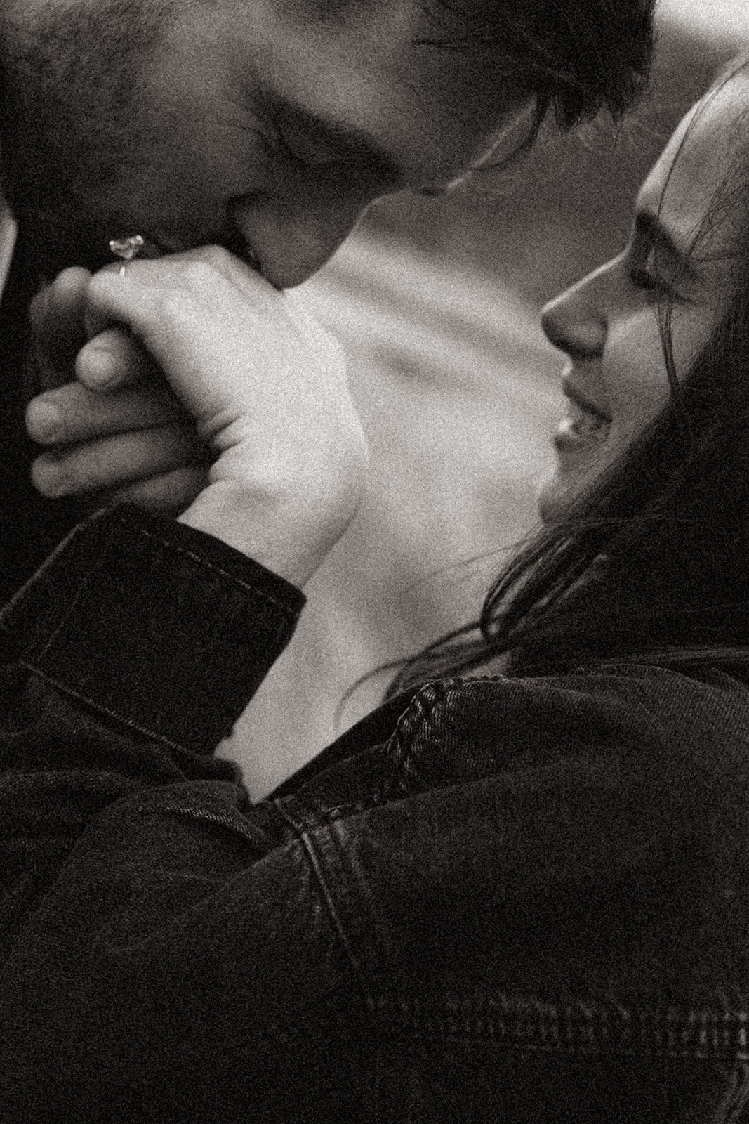 Black and white photo of man kissing womans hand as she smiles