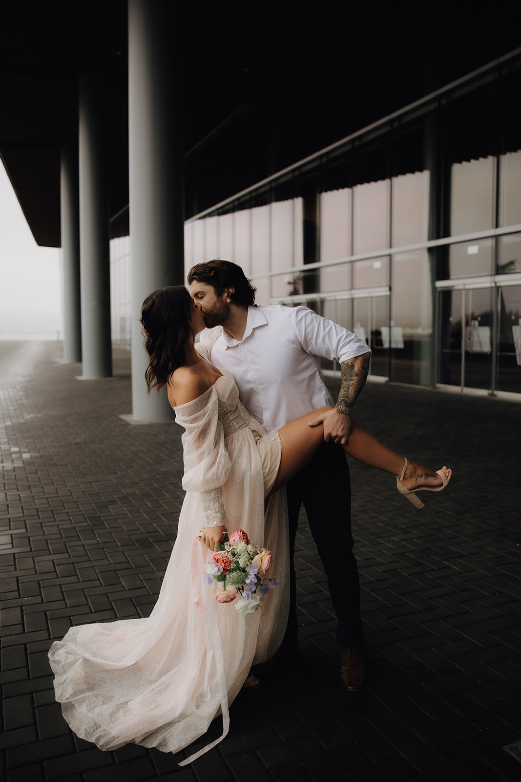 A couple sharing an intimate kiss during their Vancouver elopement, the modern architecture of the downtown area adds a dramatic backdrop, enhancing the romantic moment.