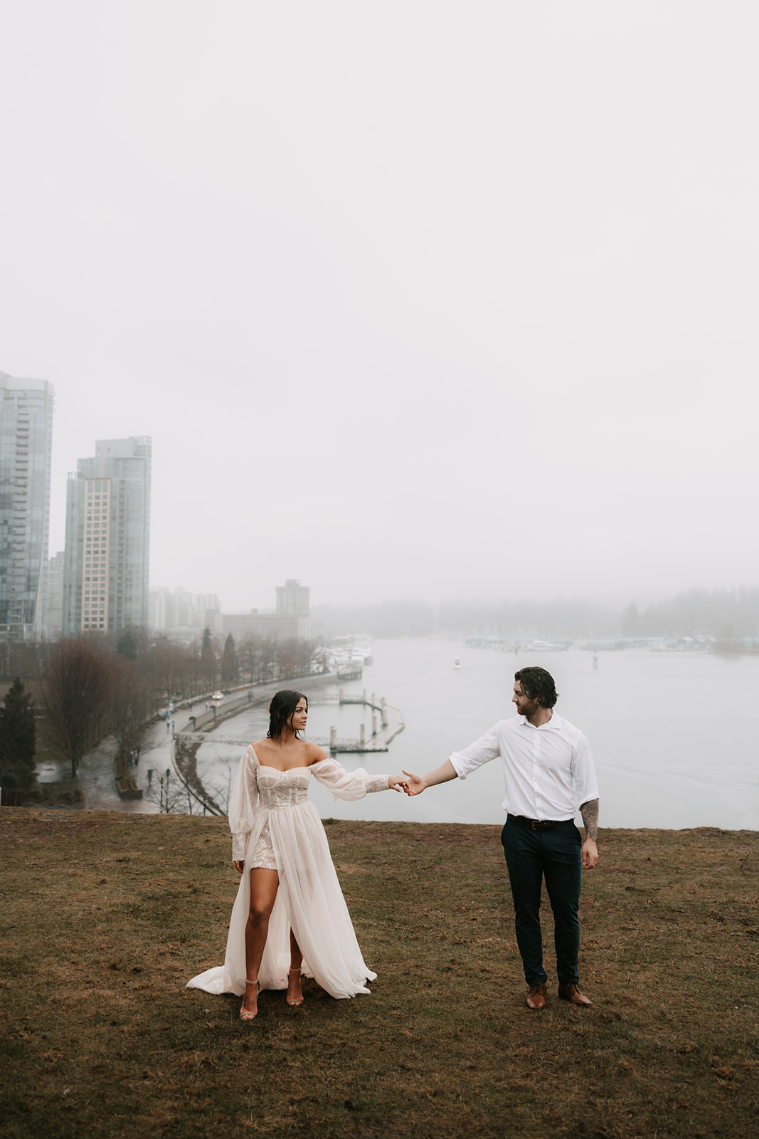 Bride and groom holding hands with the skyline of Vancouver behind them