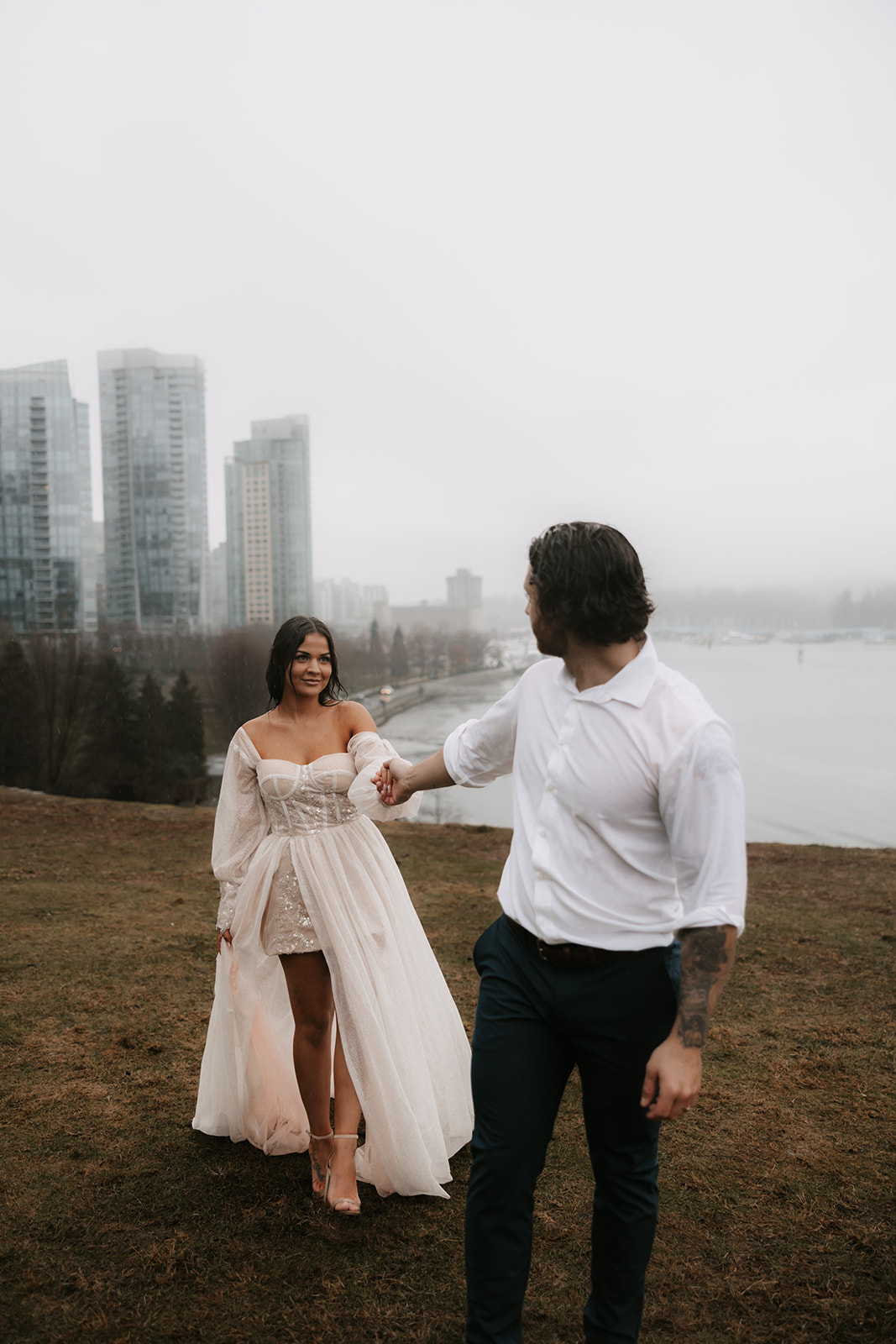 Bride and groom holding hands with the skyline of Vancouver behind them