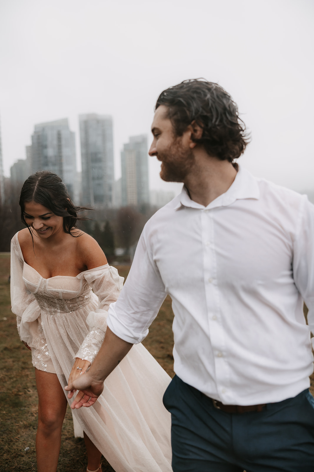 Bride and groom laughing as they walk in the rain during their elopement