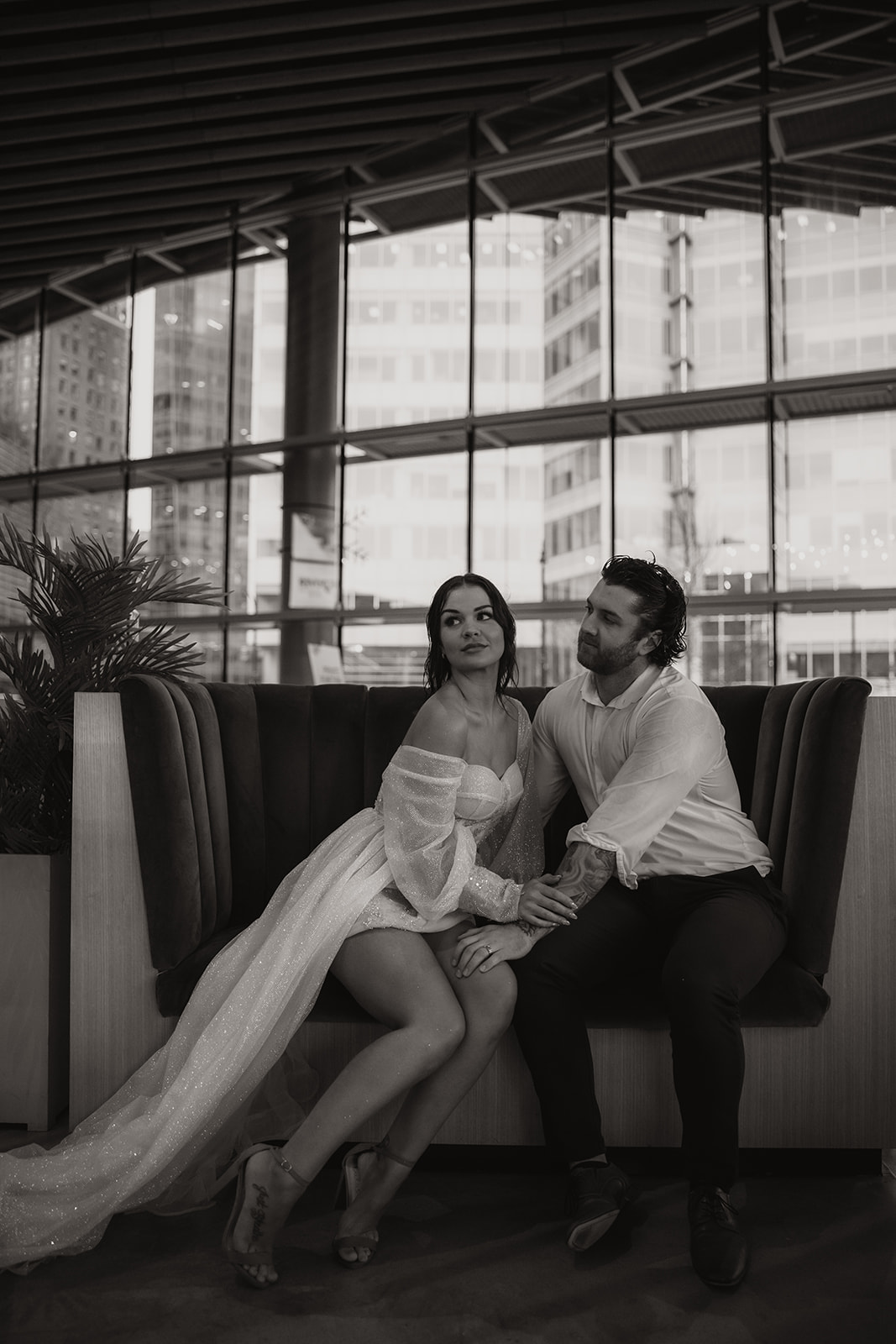 Black and white photo of bride and groom sitting down in a hotel