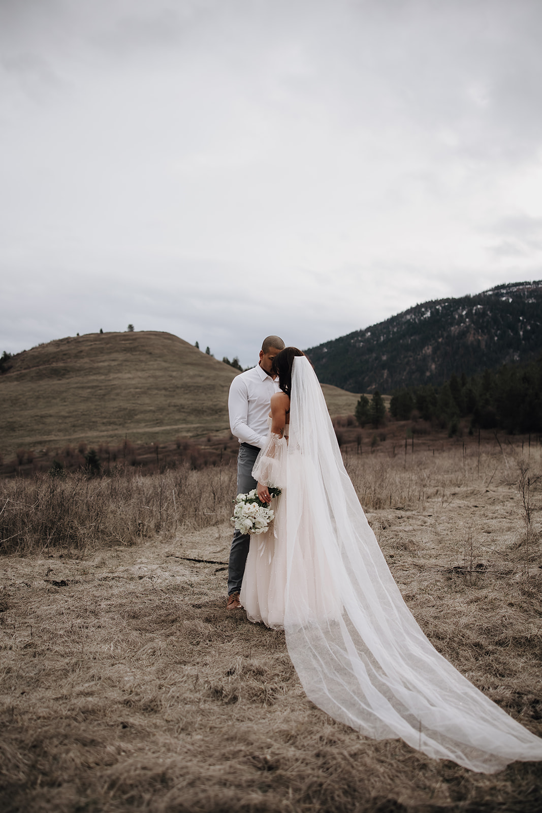 A couple shares an intimate kiss against a beautiful backdrop of rolling hills in the Okanagan region during their Okanagan elopement.