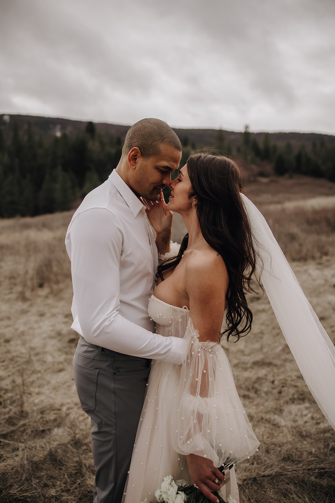 The bride and groom share a loving moment as the couple gazes into each other's eyes in the natural beauty of their Okanagan elopement.