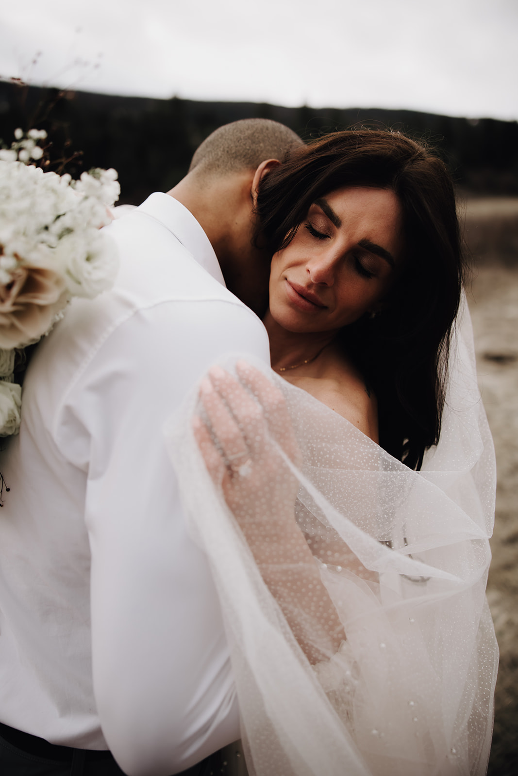 A close-up of the couple embracing during their Okanagan elopement, with the bride's veil and soft bridal gown adding a dreamy touch to the moment.