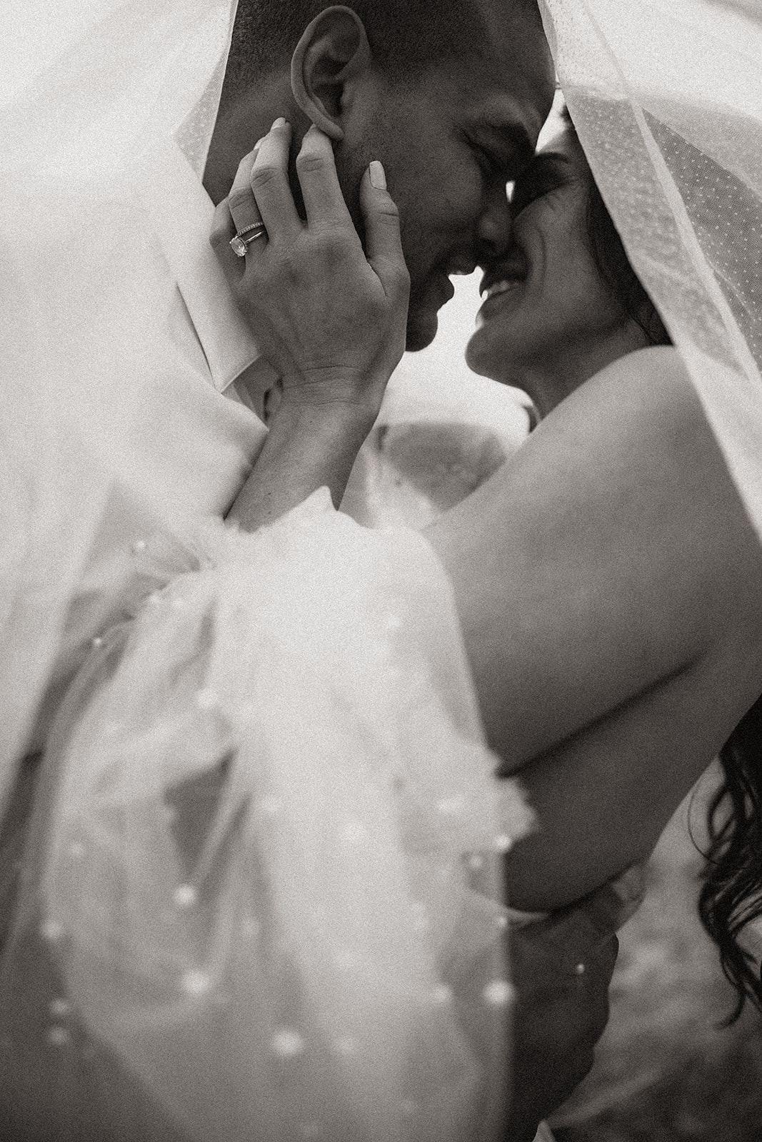 A close-up of the bride and groom sharing a quiet moment, the bride's veil cascading down her shoulders, captured during their Okanagan elopement near the lake.