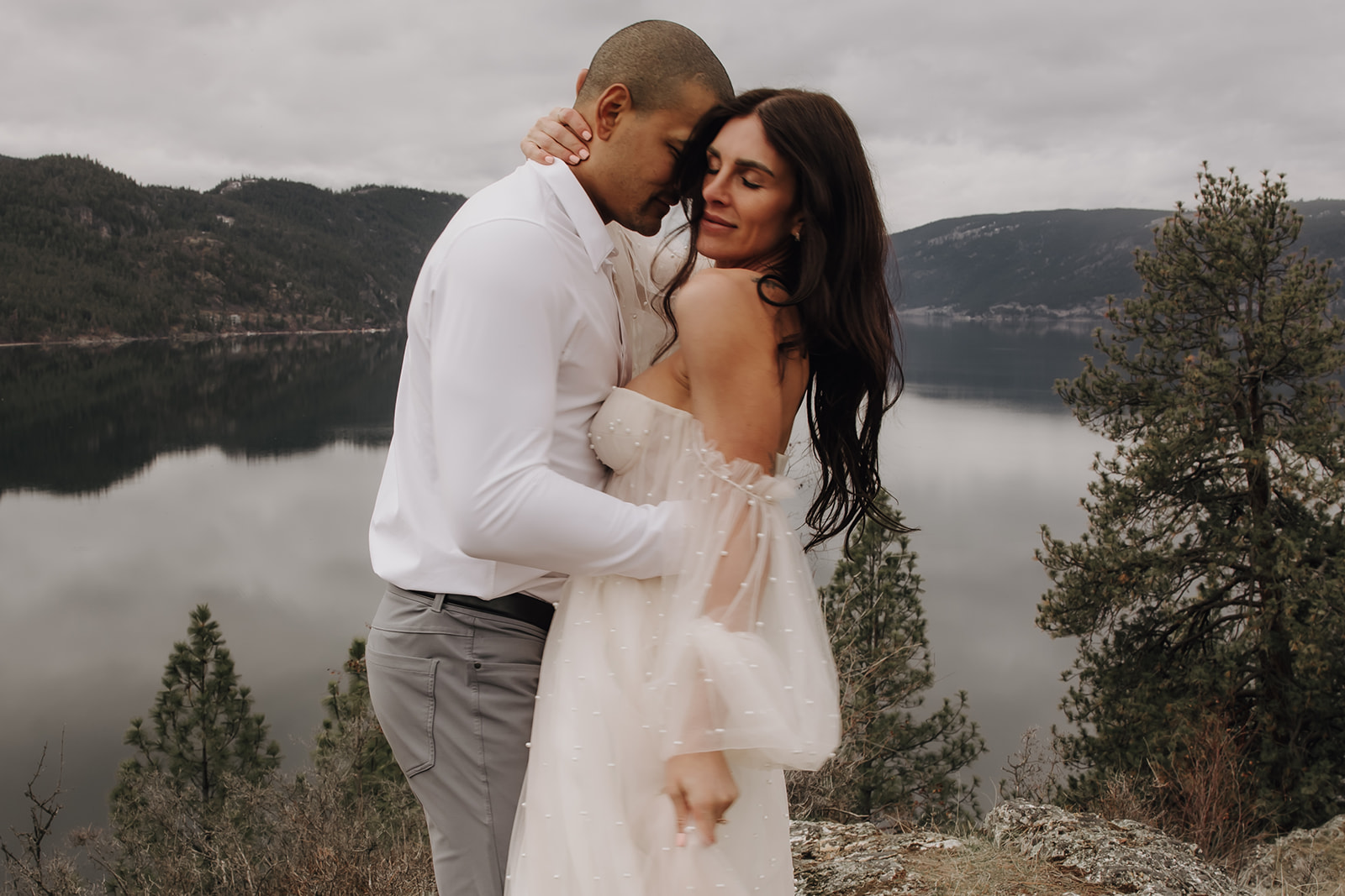 Bride and groom cuddling in a romantic embrace during their Okanagan elopement, surrounded by nature and the dramatic landscape of the Okanagan Valley.

