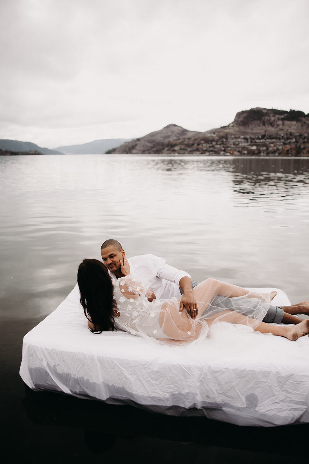 A beautiful lake setting provides the backdrop for this unique engagement photo idea, with the couple sharing a tender moment on an air mattress in the middle of the water.