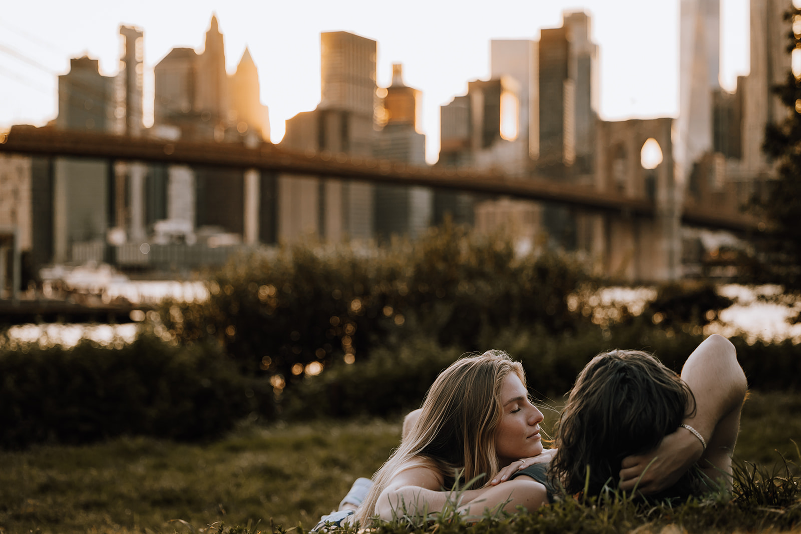 The couple relaxing on the grass with the skyline in the distance, showcasing a serene moment from their new york city couple photoshoot.