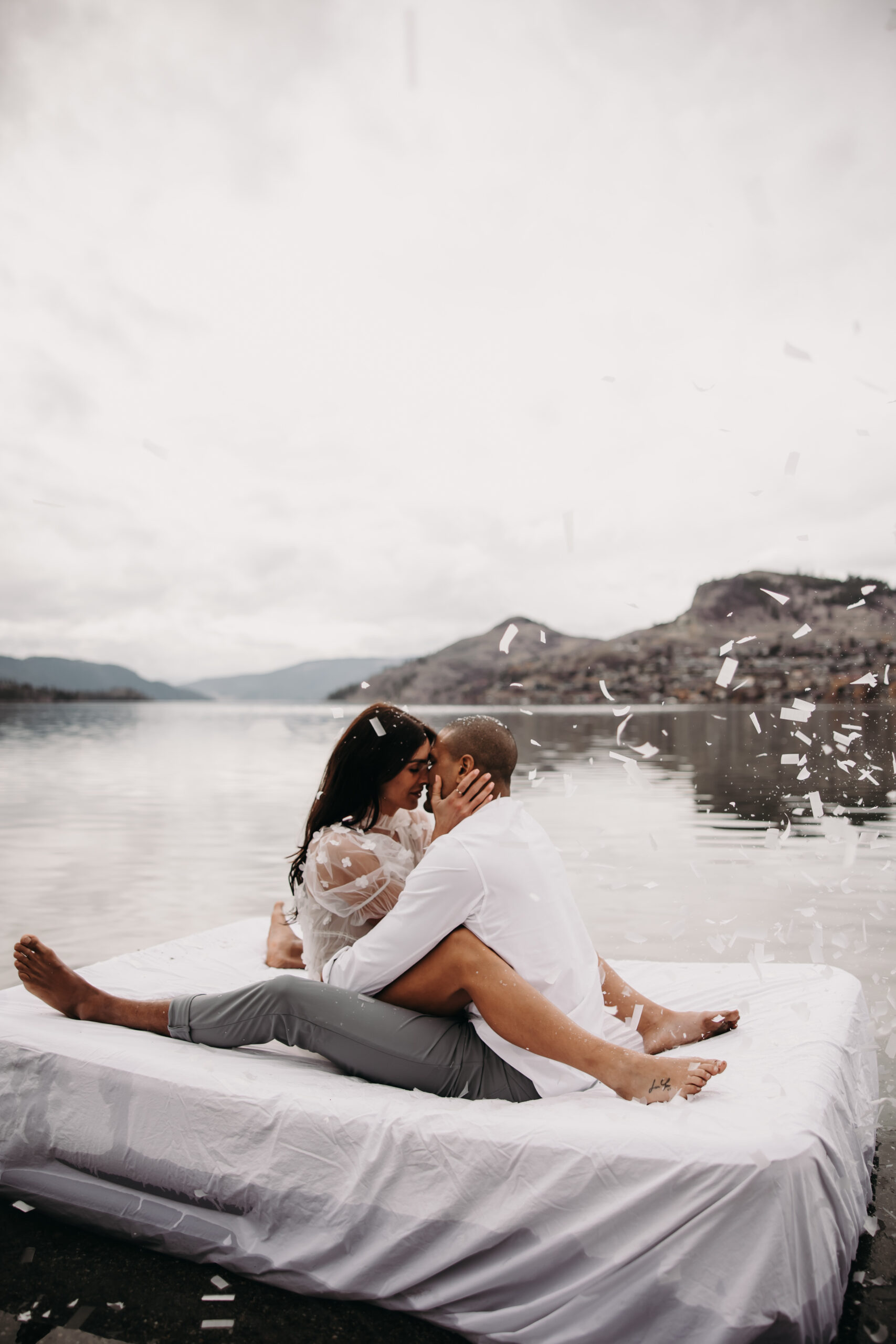 Unique engagement photo ideas take a fun twist with a playful moment captured on a mattress in the lake, showing the couple's carefree, loving nature.