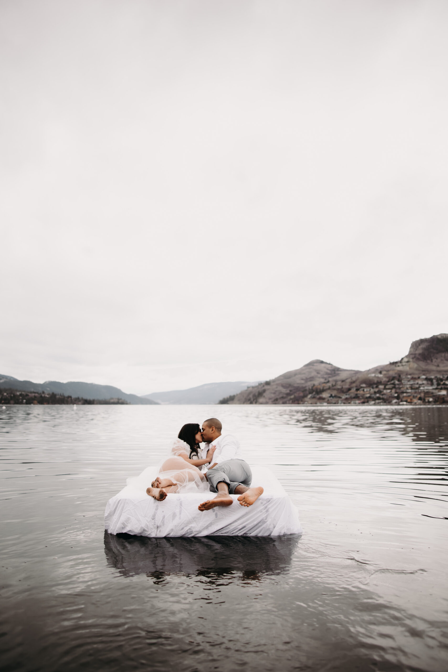 A breathtaking unique engagement photo idea shows the couple surrounded by nature, confetti in the air, and the serenity of the lake as they embrace on an air mattress