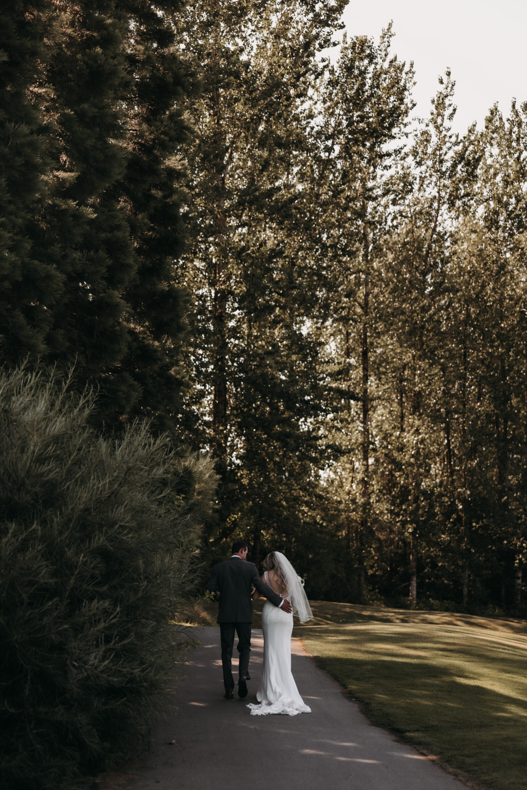 Bride and groom walking away from the camera into a forest of trees