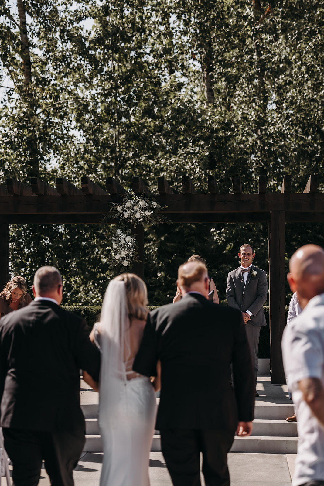 The emotional moment as the bride approaches the groom at the Redwoods Golf Course wedding venue, with sunlight filtering through the trees.