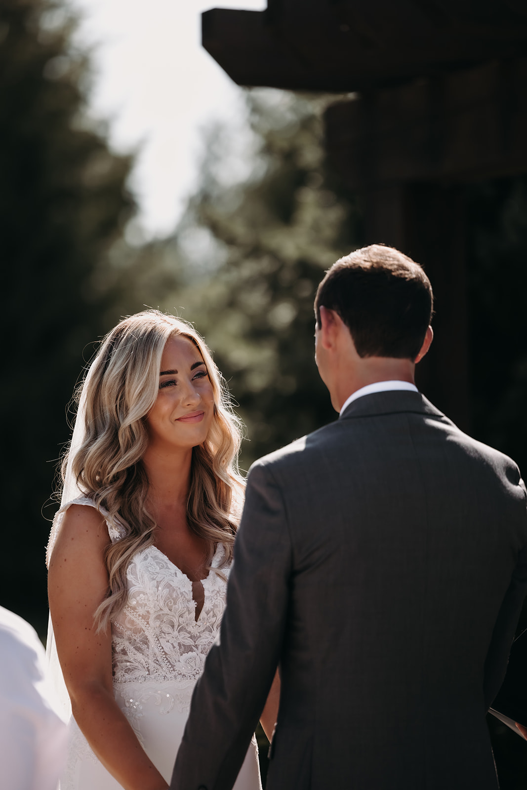 A bride smiling softly at her groom during their ceremony at the Redwoods Golf Course wedding, exchanging heartfelt vows under the serene tree-filled backdrop.