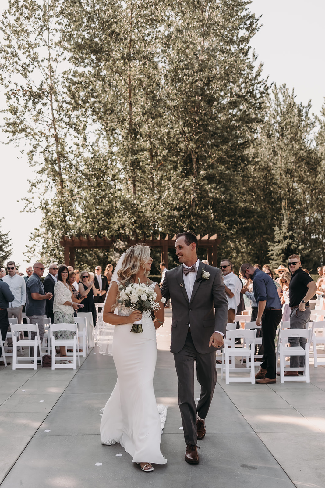 The bride and groom walking down the aisle together after their Redwoods Golf Course wedding ceremony, smiling and holding hands while guests applaud.