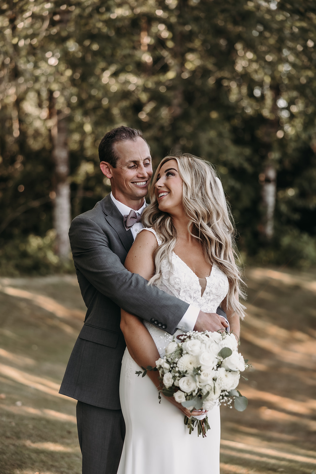 The bride and groom share a loving embrace, their faces close together as they smile happily during their wedding day at the Redwoods Golf Course wedding venue.