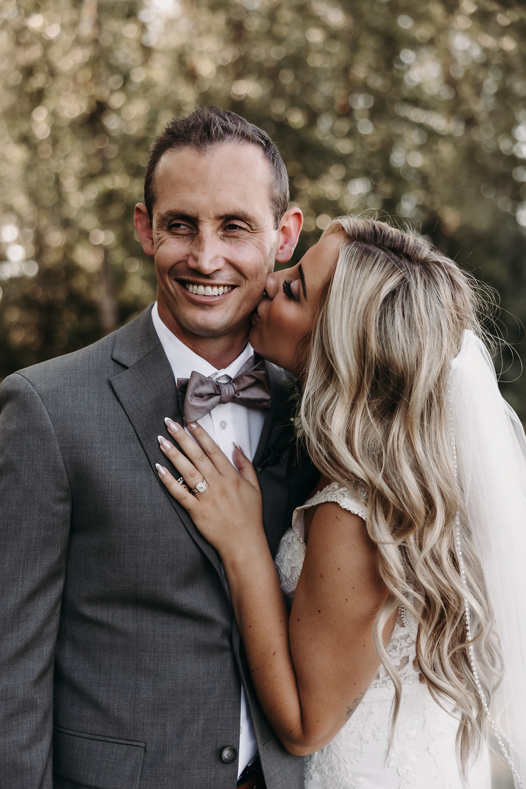 A joyful moment of the bride and groom, as the bride kisses her groom’s cheek while they stand close to each other at their Redwoods Golf Course wedding.