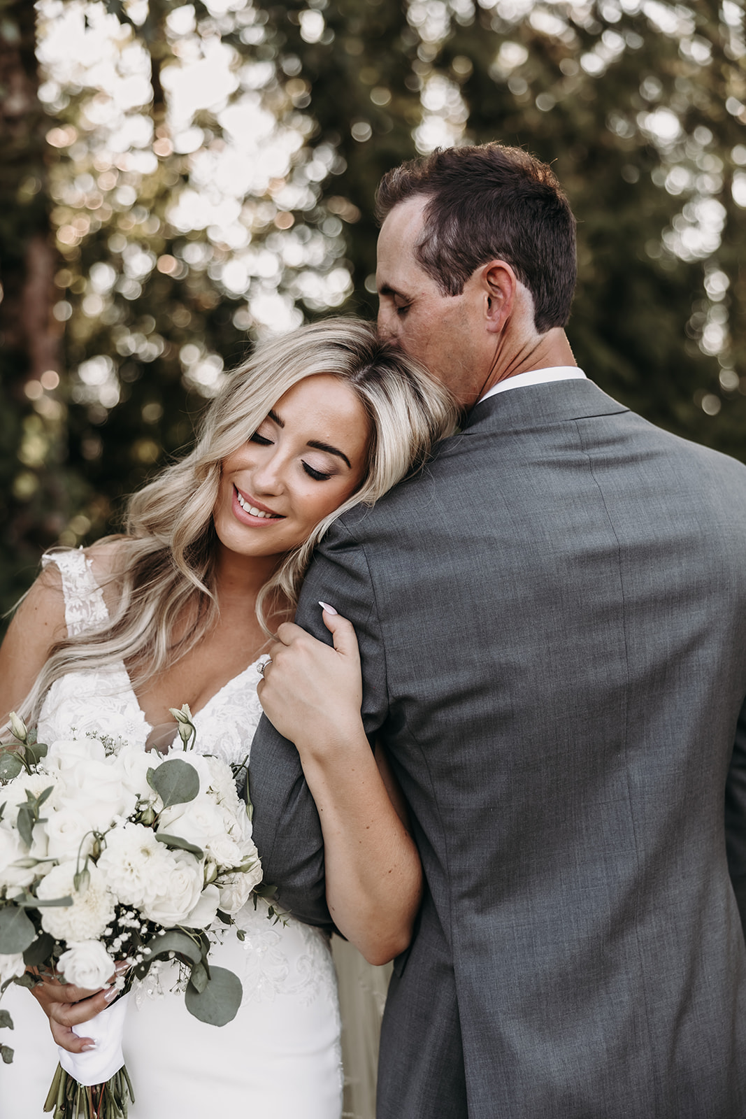 The bride and groom share a loving embrace, their faces close together as they smile happily during their wedding day at the Redwoods Golf Course wedding venue.